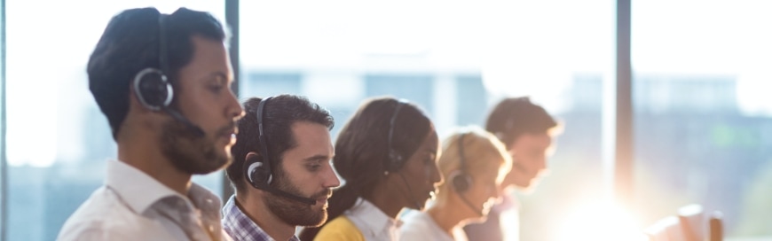 people sitting next to each other wearing phone call headsets in office